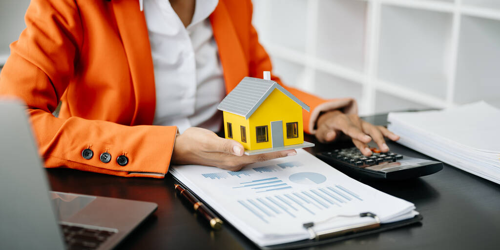 Makler präsentiert und berät den Kunden zur Entscheidungsfindung unterzeichnen Versicherungsformularvertrag, Hausmodell, betreffend Hypothekendarlehensangebot im Büro - Foto, Bild
