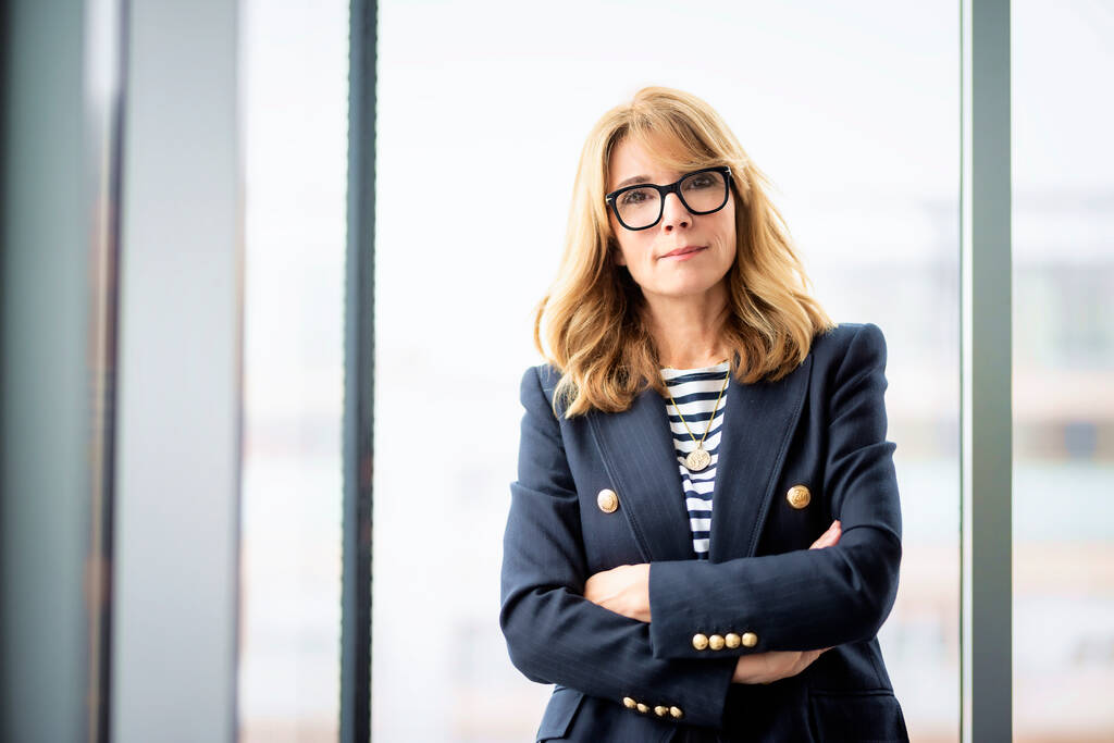 Close-up of confident businesswoman standing with arms crossed in a modern office. Professional female wearing eyewear and blazer - Photo, Image