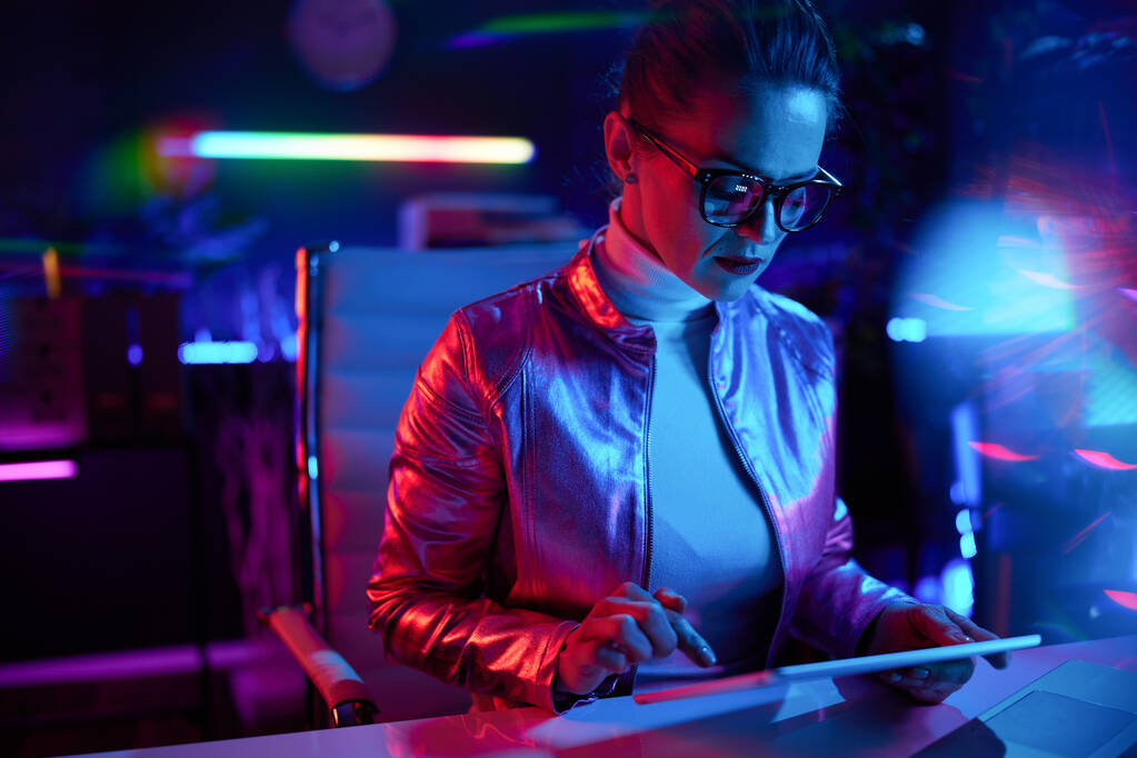 Concepto futurista neón metaverso. mujer elegante en gafas usando tableta PC en la oficina moderna. - Foto, imagen