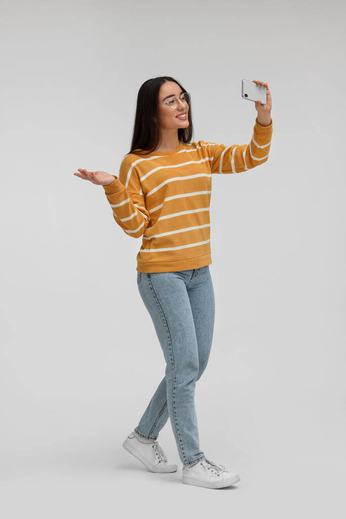 glimlachende jonge vrouw het nemen van selfie met smartphone op witte achtergrond - Foto, afbeelding