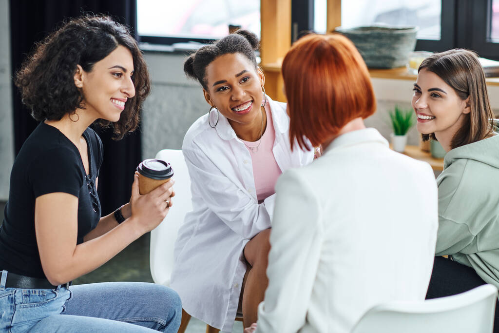multiraciální žena sedí s kávou jít a poslouchat zrzka psycholog spolu s optimistickými multietnické přítelkyně během terapie, porozumění, podporu a duševní zdraví koncept - Fotografie, Obrázek