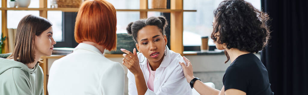 upset african american woman talking to motivation coach and multicultural female friends during psychology session in consulting room, problem-solving and mental wellness concept, banner - Photo, Image