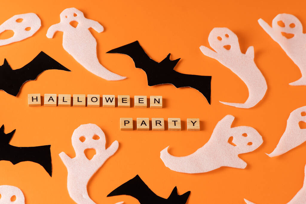 ハロウィンパーティーのための白い幽霊とバットクラフト。オレンジの背景に紙の幽霊をラッピングトップビュー。漫画の不気味なささやき。手作りのDIYハンド。文字をセットします。単語木製の文字のフレーズ. - 写真・画像