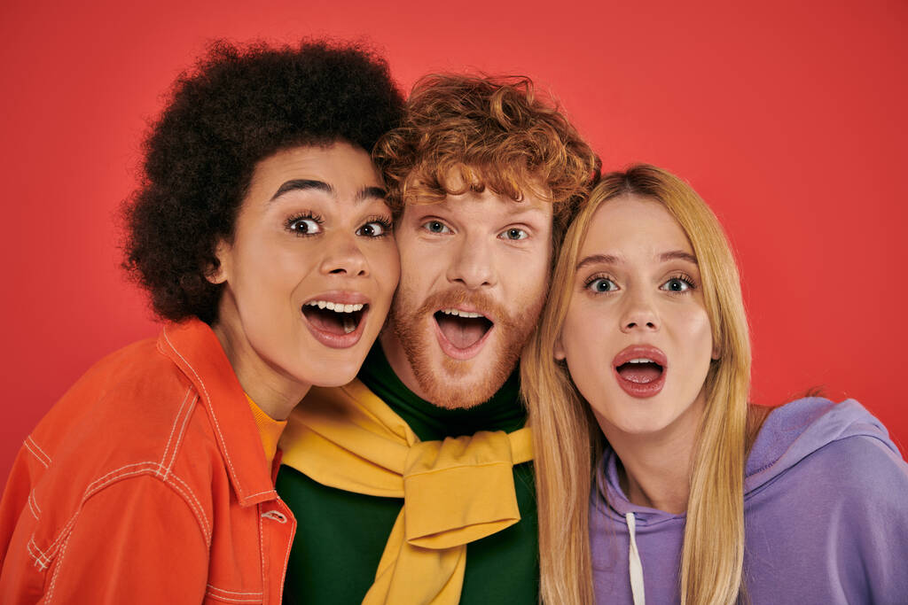 polyamorous concept, portrait of young man and multicultural women on coral background, studio shot, vibrant colors, love triangle, bonding and acceptance, excited polygamy lovers  - Photo, Image