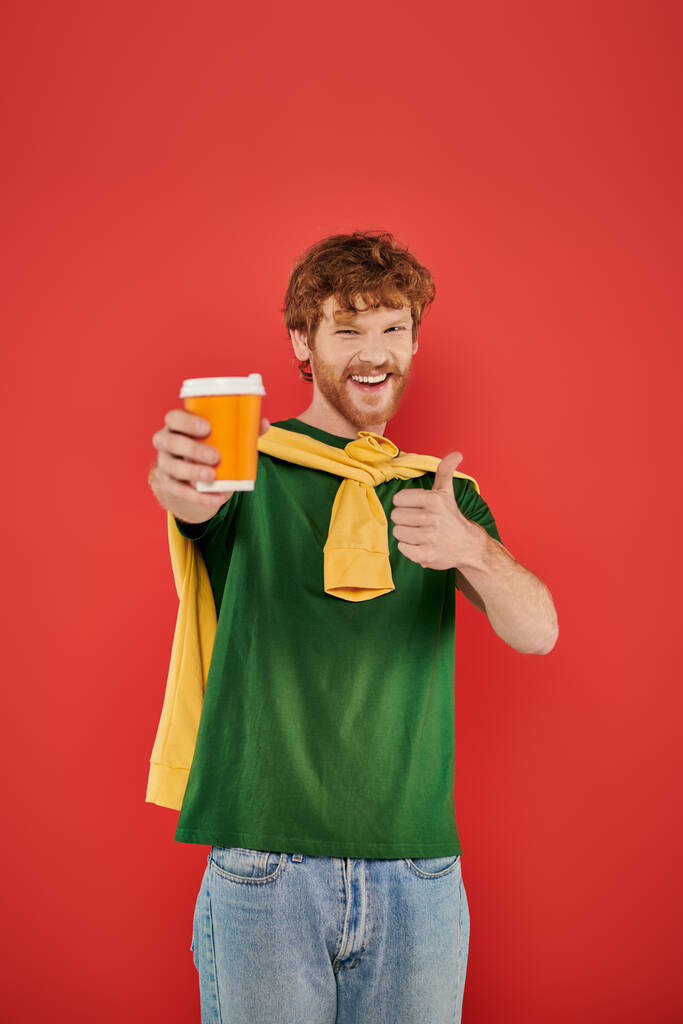 morning coffee, energy, like, redhead man with beard and curly hair holding paper cup on coral background, vibrant colors, male fashion, takeaway drink, male portrait, hot beverage - Photo, Image