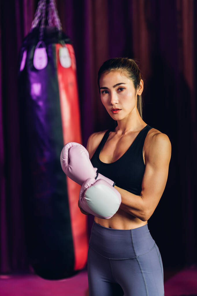 Обучение боксёров в боксерском клубе. Женщина-боксёр тренируется в спортзале. Сильная мускулистая женщина практикует коробку в розовых боксёрских перчатках в спортзале. - Фото, изображение