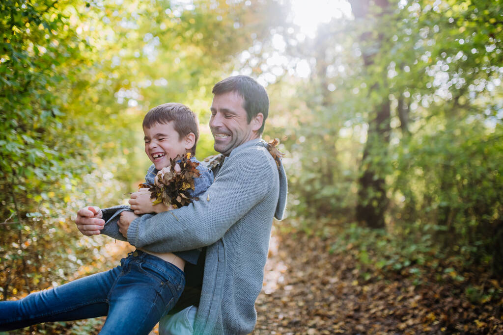 Père avec ses enfants s'amusant en forêt, jetant du feuillage. - Photo, image