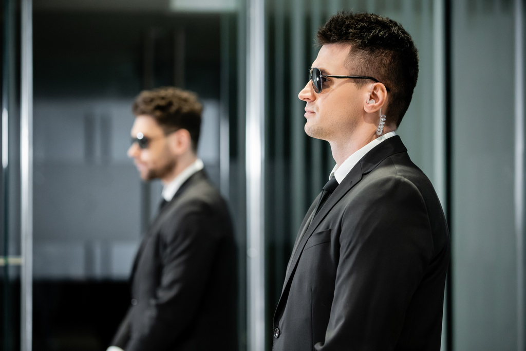 bodyguard service, private security, professional in suit and sunglasses standing in hotel lobby near work partner, earpiece, communication, luxury hotel, vigilance, protection and work, side view - Photo, Image