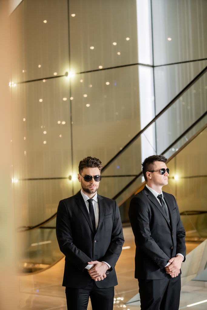 security management of hotel, two handsome men in formal wear and sunglasses, bodyguards on duty, safety measures, vigilance, suits and ties, private security, strong guards, luxury living  - Photo, Image
