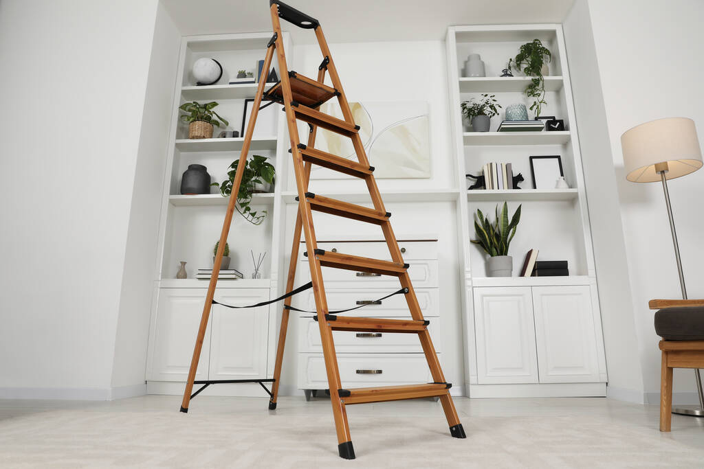 Escalera plegable de madera cerca de cajones y estantes con accesorios en la habitación, vista de ángulo bajo - Foto, Imagen