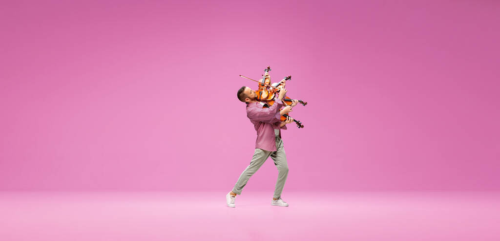 Creative collage. Talented, emotional young man playing violin against pink studio background. Concept of music, talent, hobby, entertainment, festival, performance, ad - Photo, Image