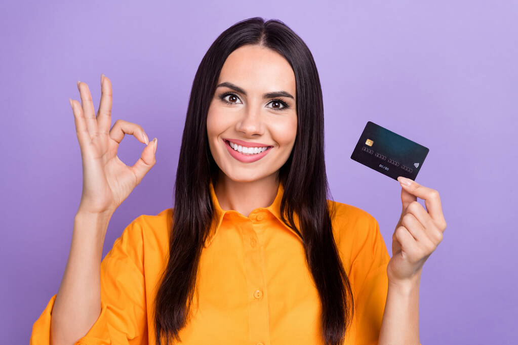 Portret młodej atrakcyjnej brunetki włosy biznesu kobieta pokazać okey znak trzymać karty debetowej wysoki zysk izolowany na fioletowym tle koloru. - Zdjęcie, obraz