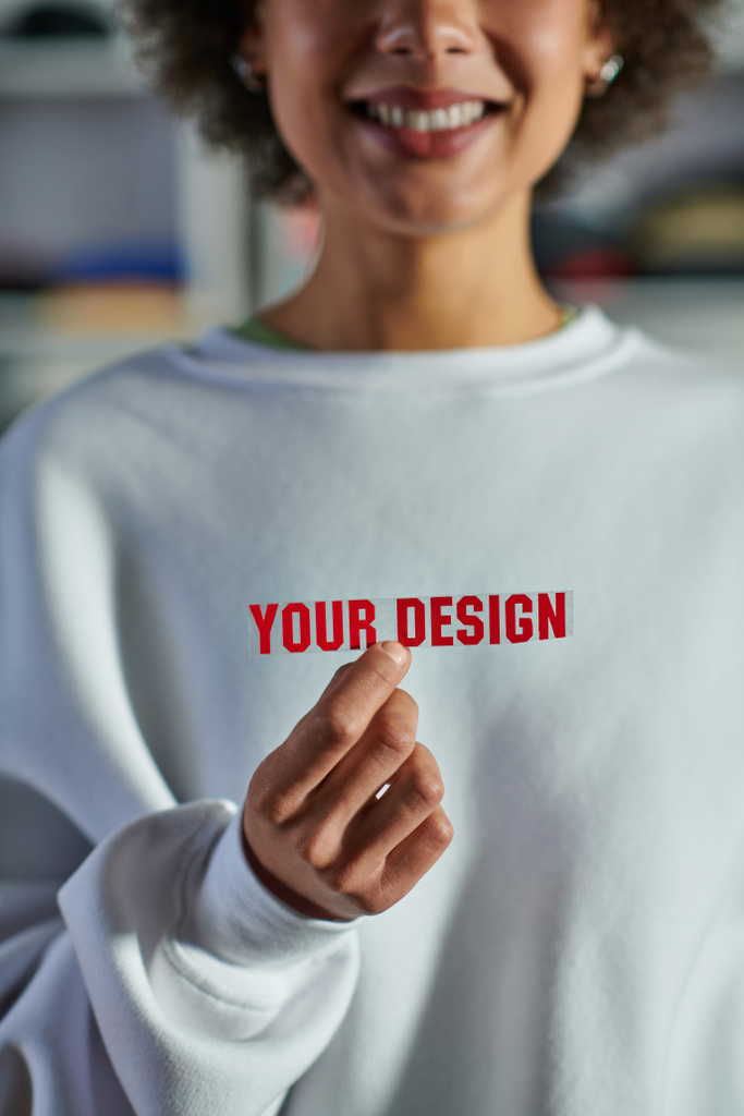 Cropped view of smiling blurred african american designer in sweatshirt holding printing layer with your design lettering in print studio, focused business owner managing workshop - Photo, Image
