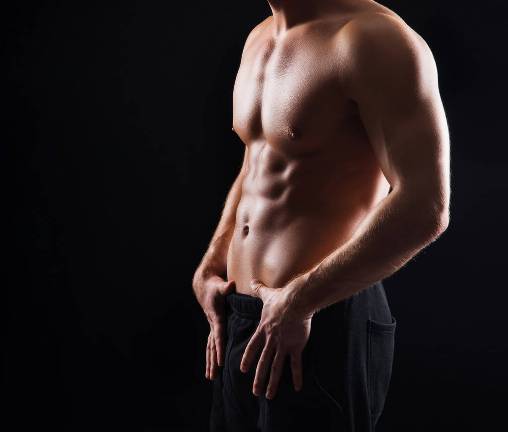Erős, fitt és sportos testépítő férfi fekete háttér felett. Sport és fitness koncepció - Fotó, kép