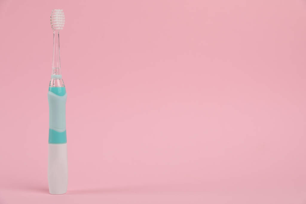 Elektrische tandenborstel op roze achtergrond, ruimte voor tekst - Foto, afbeelding