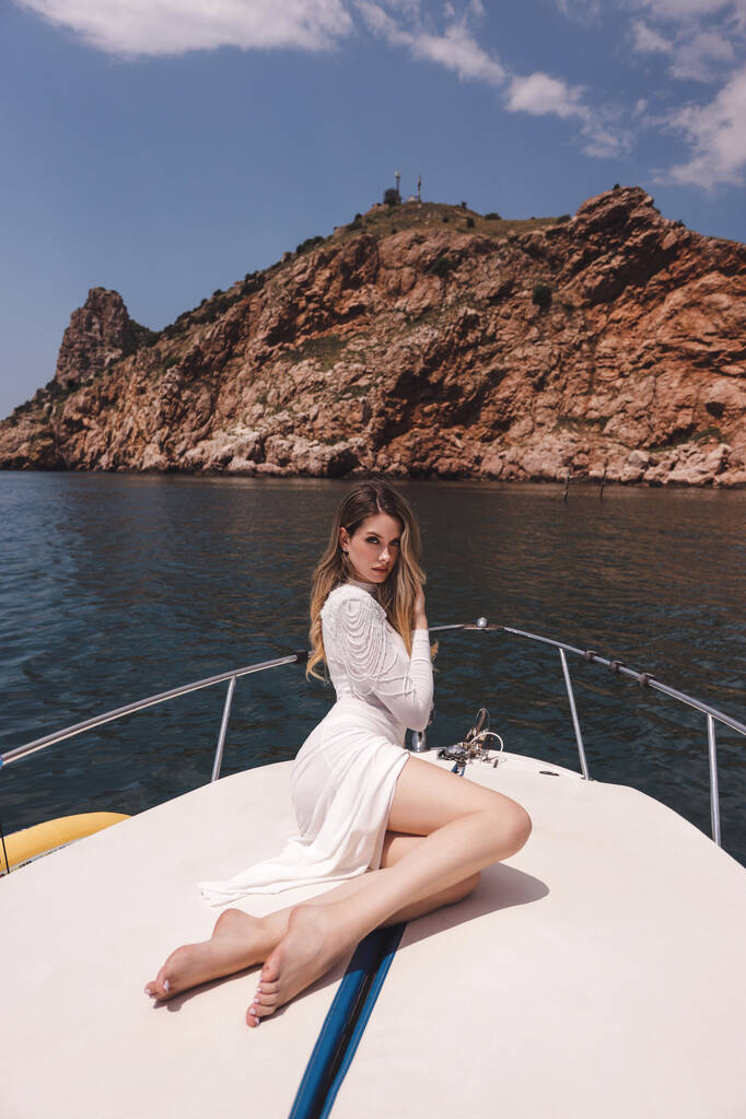 moda de mulher bonita com cabelos escuros em vestido branco luxuoso relaxante no convés do iate, navegando no mar Mediterrâneo - Foto, Imagem
