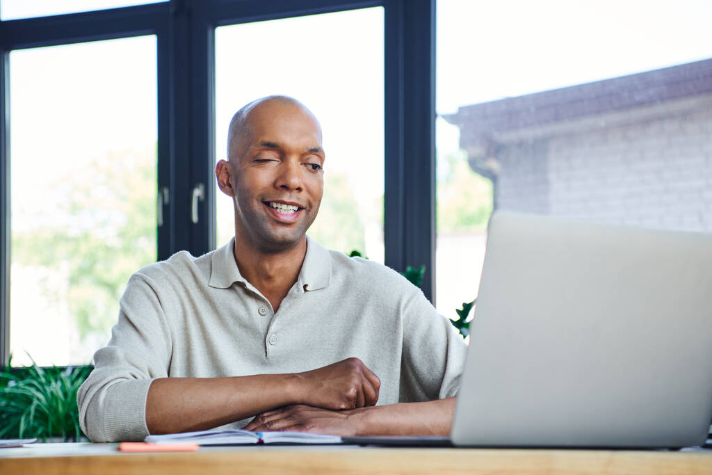 chronic illness, positive african american businessman with eye syndrome looking at laptop on desk, myasthenia gravis, bold and dark skinned office worker, inclusion, diversity in society  - Photo, Image