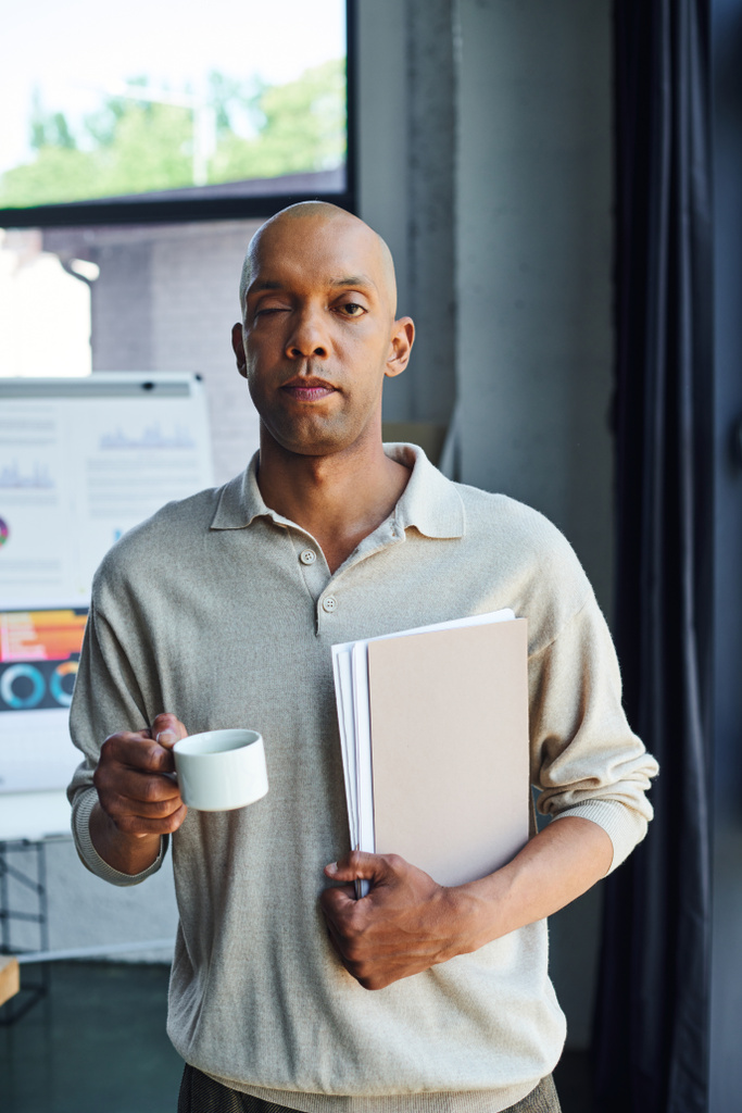 афроамериканський чоловік з хворобою міастенії, що тримає папку і чашку кави, сміливий і темношкірий офісний працівник з синдромом птозу очей, включенням, професійними пострілами  - Фото, зображення