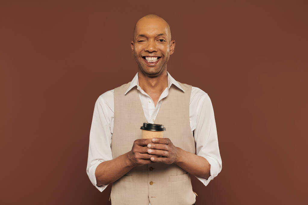 integracja, szczęśliwy i śmiały Afrykański Amerykanin z zespołem miastenii, stojący z papierową filiżanką, ciemnoskóry mężczyzna z przewlekłą chorobą na brązowym tle, kawa na wynos  - Zdjęcie, obraz