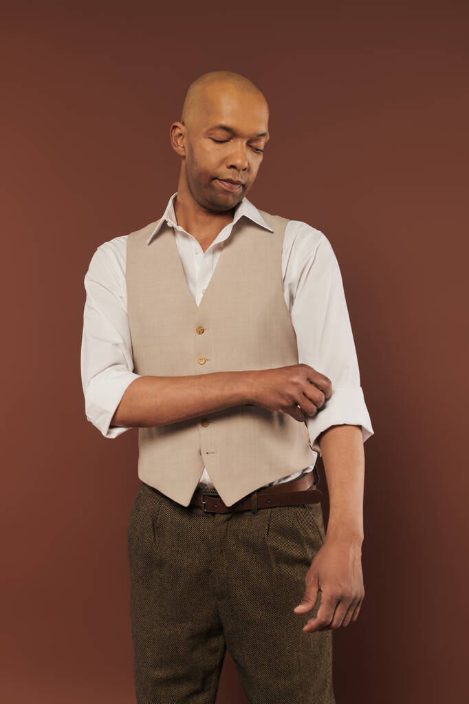 bold african american man with myasthenia gravis standing on brown background, adjusting sleeve on white shirt, dark skinned, diversity and inclusion, real people, physical impairment  - Photo, Image