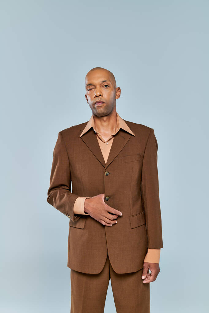 oogsyndroom, stoere Afro-Amerikaanse man met myasthenia gravis kijkend naar camera op grijze achtergrond, donkere huid in formele kleding, diversiteit en inclusie, echte mensen, portret  - Foto, afbeelding