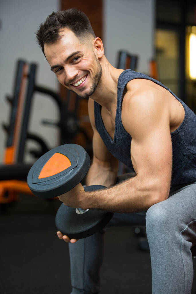 homme heureux avec haltères muscles fléchissants dans la salle de gym - Photo, image