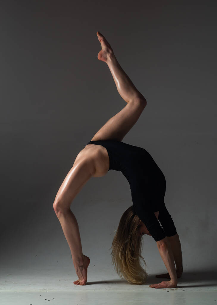 Sexy dívka dělá gymnastická cvičení pro strečink. Krásná sexy ohebná žena předvádí sexy ohebné tělo. Pružnost táhnoucí se na černém pozadí. Silné flexibilní sexy ženské tělo - Fotografie, Obrázek