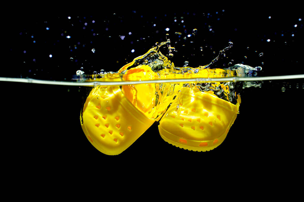 Kyiv, Ukraine - June 6, 2023: Small Crocs Shoes Submerged in Water with Splashes on Black - Photo, Image