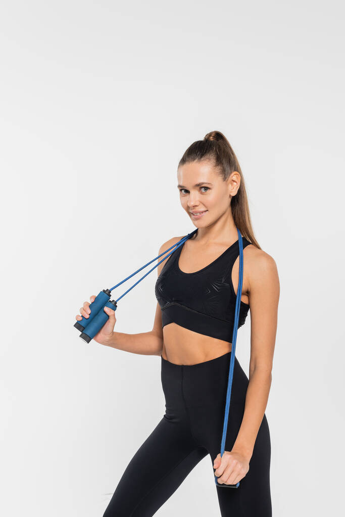 Cheerful woman holding skipping rope and looking at camera isolated on white, fit concept - Photo, Image