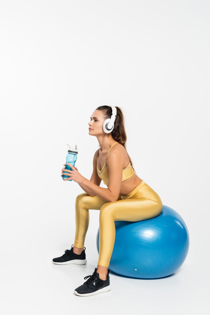 zdrowy tryb życia, aerobik, kobieta w aktywnym zużyciu i słuchawki bezprzewodowe siedzi na piłce fitness  - Zdjęcie, obraz