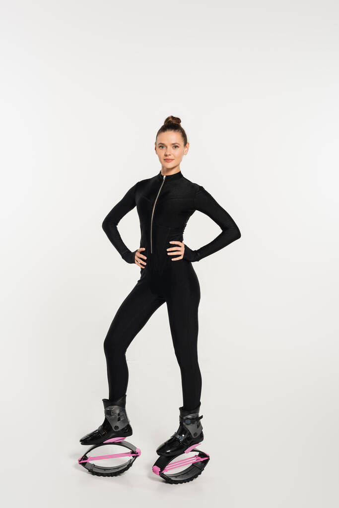 donna in jumping boots su sfondo bianco, sportiva con corpo tonico in tuta nera - Foto, immagini