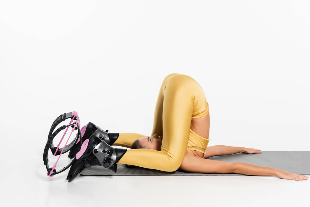 donna flessibile in abbigliamento attivo che allunga il corpo sul tappeto fitness, scarpe da salto kangoo, motivazione  - Foto, immagini