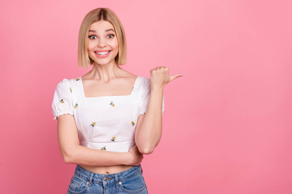Zdjęcie podekscytowany młoda dziewczyna bezpośredni kciuk palec pusty przestrzeń reklama sprzedaż off sklep zakupoholiczka nosić biały koszula odizolowany różowy kolor tło. - Zdjęcie, obraz