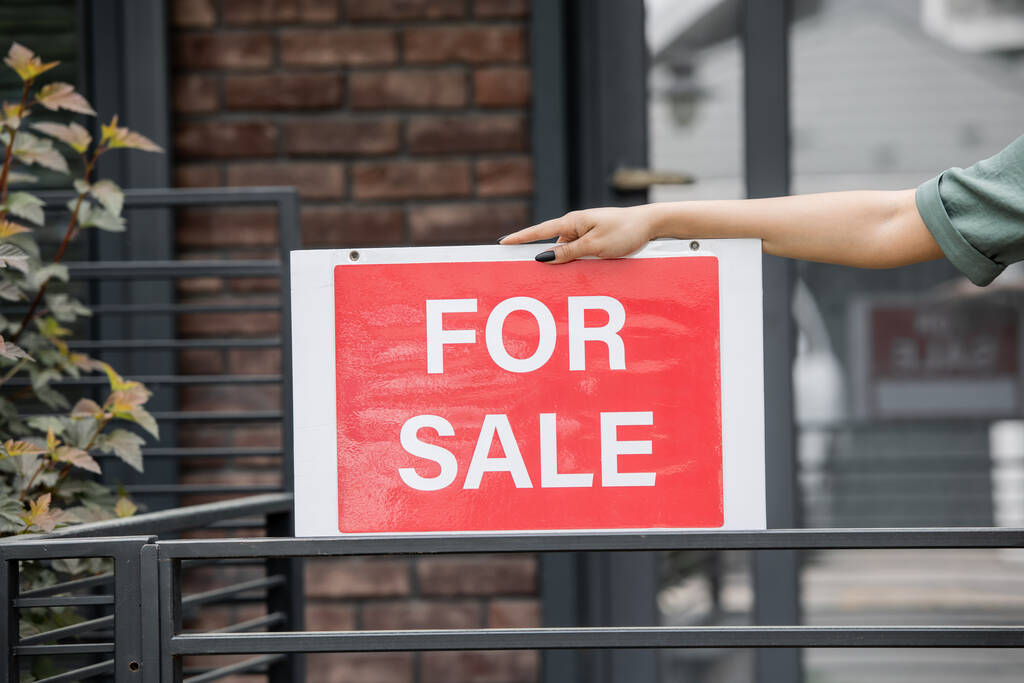 обрізаний вид афро-американського ріелтора, що тримає вивіску з продажу, розписування біля огорожі будинку - Фото, зображення