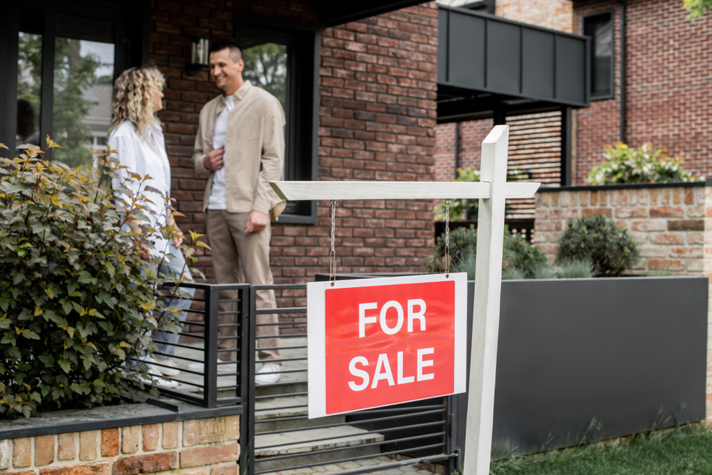 alegre y exitoso agente inmobiliario hablando con mujer cerca de casa contemporánea en venta en la calle - Foto, Imagen