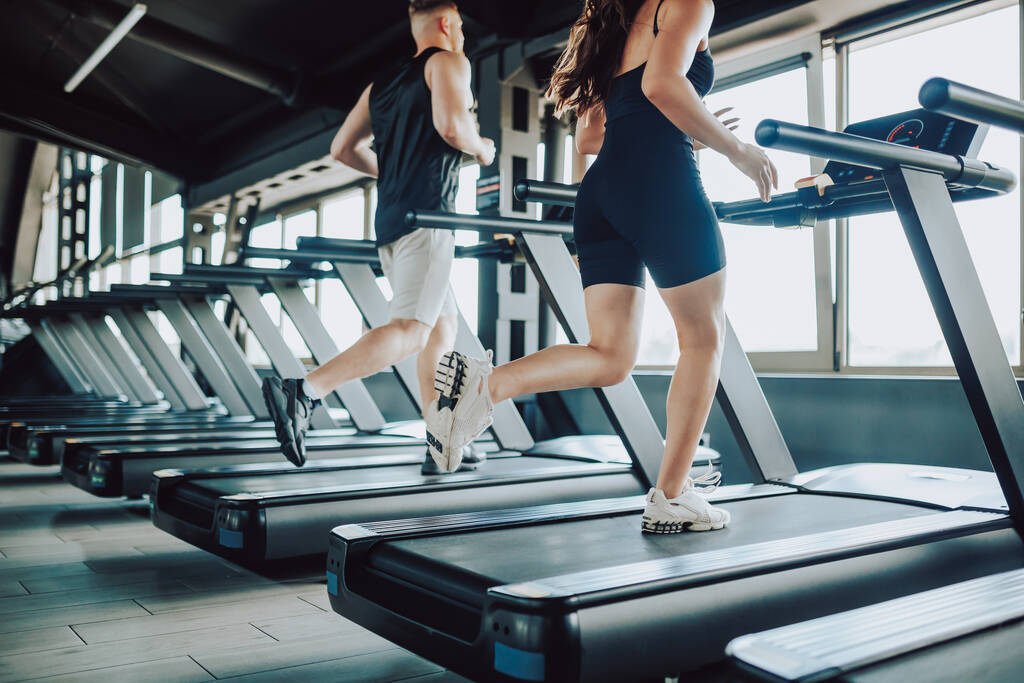 Ισπανόφωνος και αμερικανικό ζευγάρι τρέχει διάδρομο Fitness στο γυμναστήριο. Καυκάσιος και Ισπανίδα ασχολούνται με έντονη γυμναστική. Νέοι Fit Ζευγάρι Εκπαίδευση Μαζί Στο Γυμναστήριο - Φωτογραφία, εικόνα