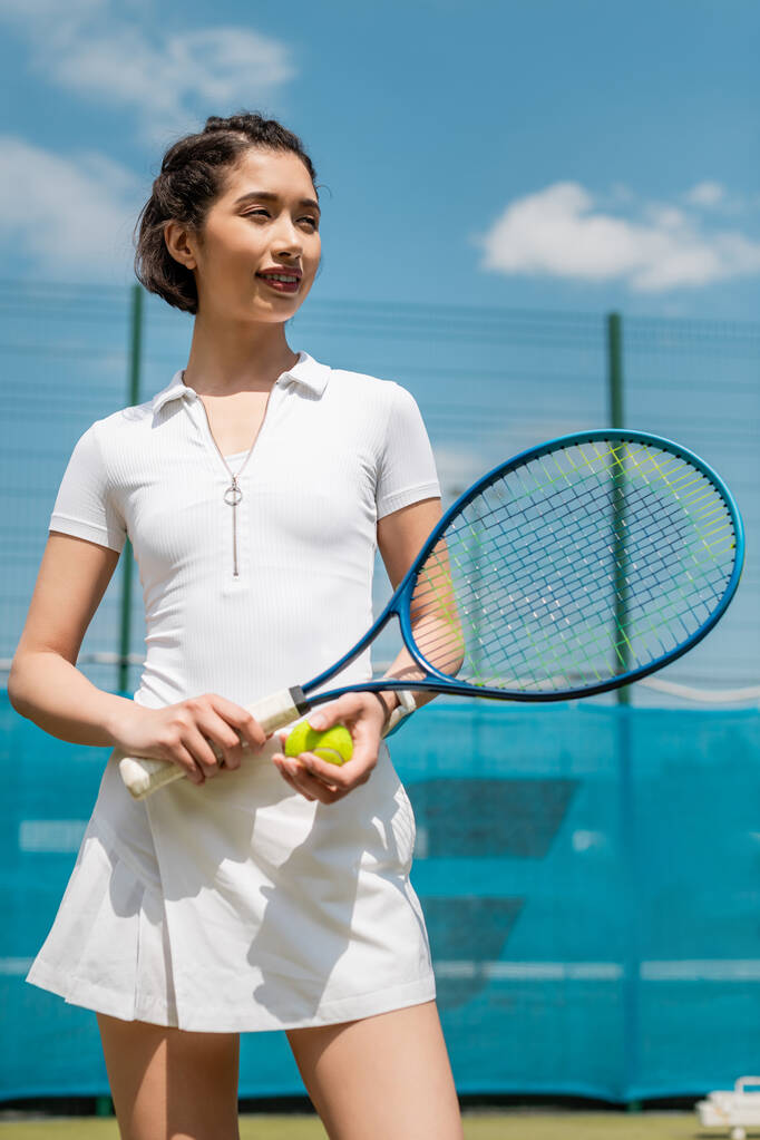 mulher feliz no desgaste ativo segurando raquete de tênis e bola, jogador no campo, esporte e motivação - Foto, Imagem