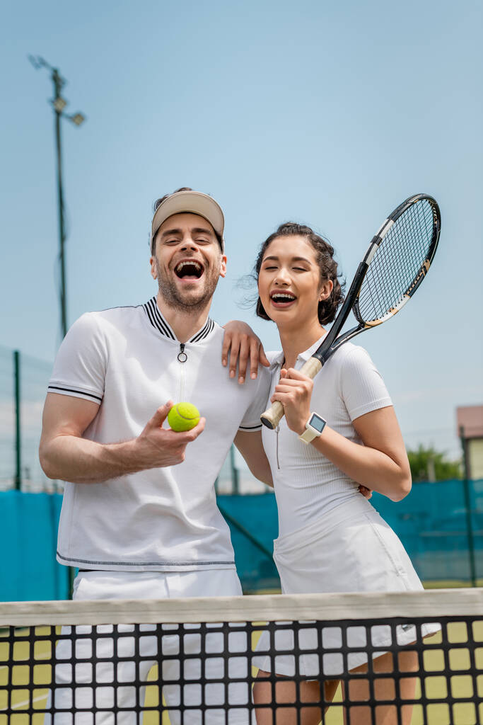 podekscytowany mężczyzna i szczęśliwa kobieta trzyma piłka tenisowa i rakieta, lato, para sport i rekreacja - Zdjęcie, obraz