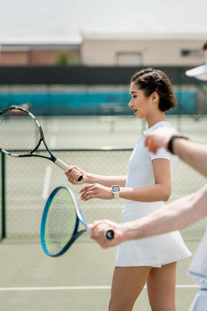 woman in tennis skirt practicing on tennis court, holding racket, boyfriend and girlfriend, sport - Photo, Image