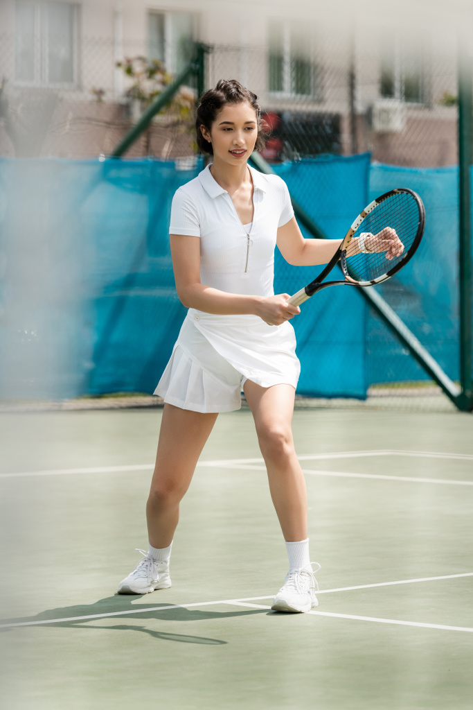 felice giocatore femminile in abito sportivo che tiene racchetta sul campo da tennis, sport estivi, hobby e salute - Foto, immagini