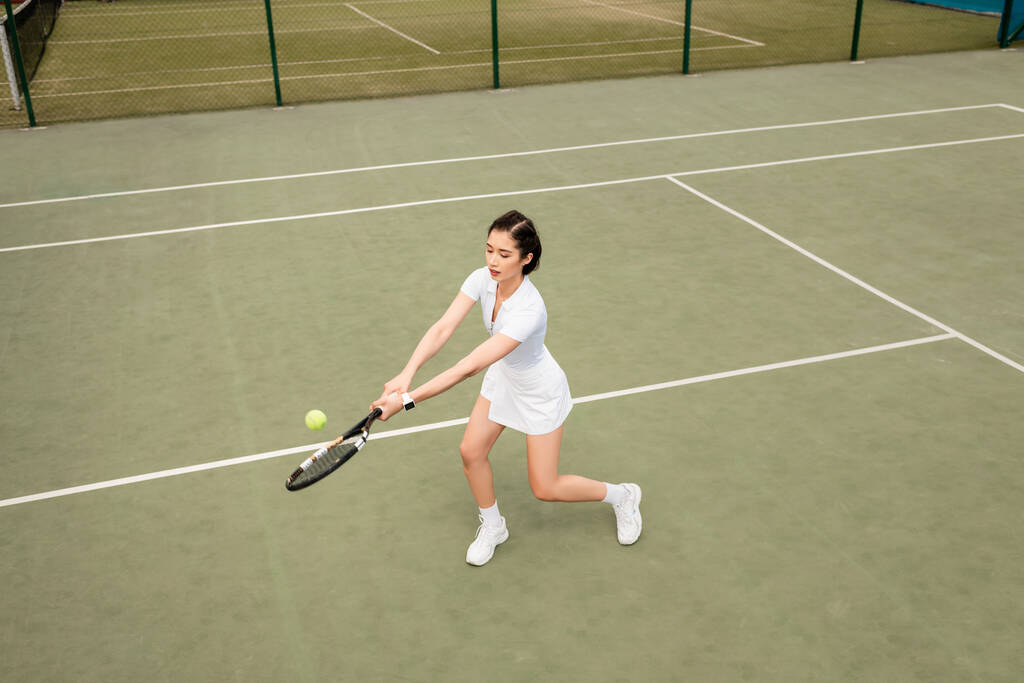 pohled shora na hráčku v aktivním oblečení hrající tenis, raketu a míček, sport - Fotografie, Obrázek