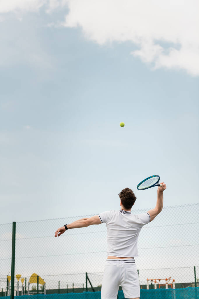 vista posteriore dell'uomo che gioca a tennis sul campo, tenendo la racchetta, colpendo palla, rovescio - Foto, immagini