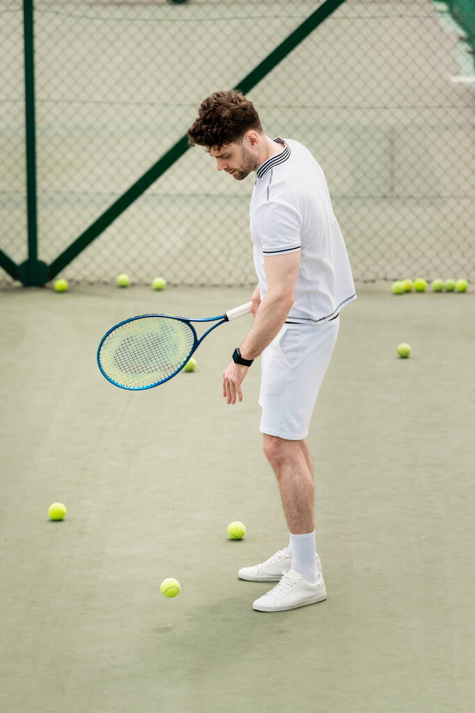 pelotas de tenis alrededor de deportista con raqueta en la cancha, hobby y recreación, jugador guapo - Foto, imagen