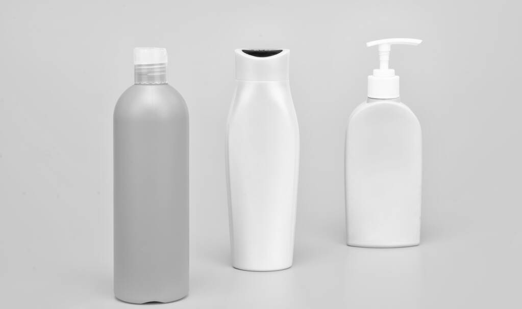 Liquid plastic containers for shampoo and bodywash cosmetic products and toiletries yellow background copy space, bottles. - Valokuva, kuva