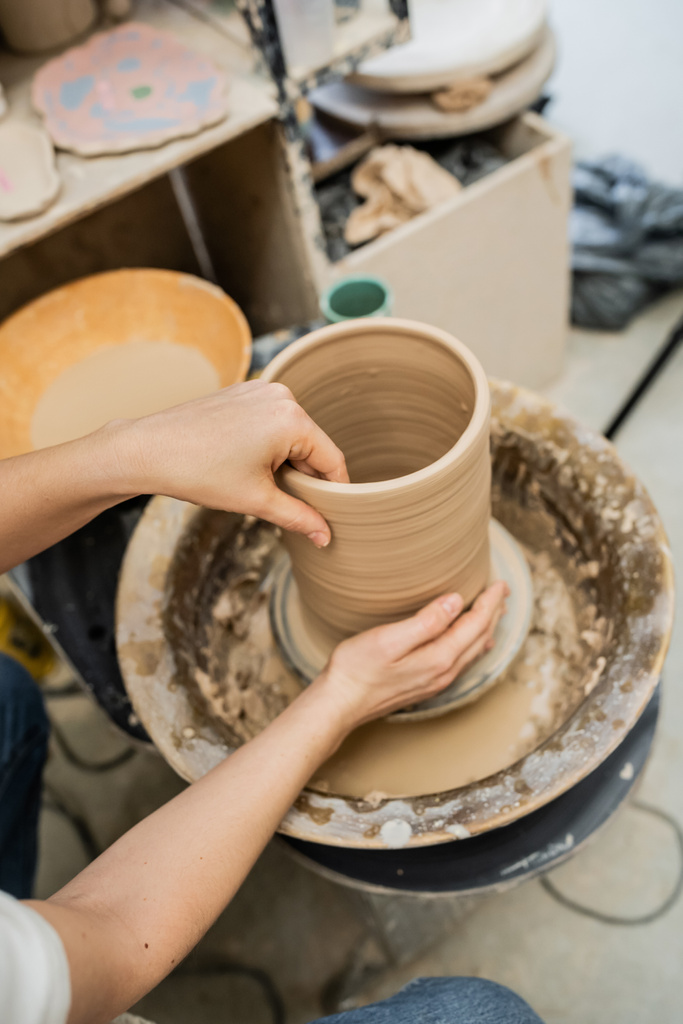 Hochwinkelblick der Kunsthandwerkerin, die Tonvase auf Töpferscheibe in der Keramikwerkstatt herstellt - Foto, Bild