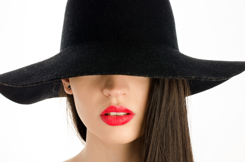 Γυναίκα με ένα μεγάλο μαύρο καπέλο που καλύπτει τα μάτια της. Τέλεια όμορφη κόκκινα χείλη, στόμα σέξι - Φωτογραφία, εικόνα