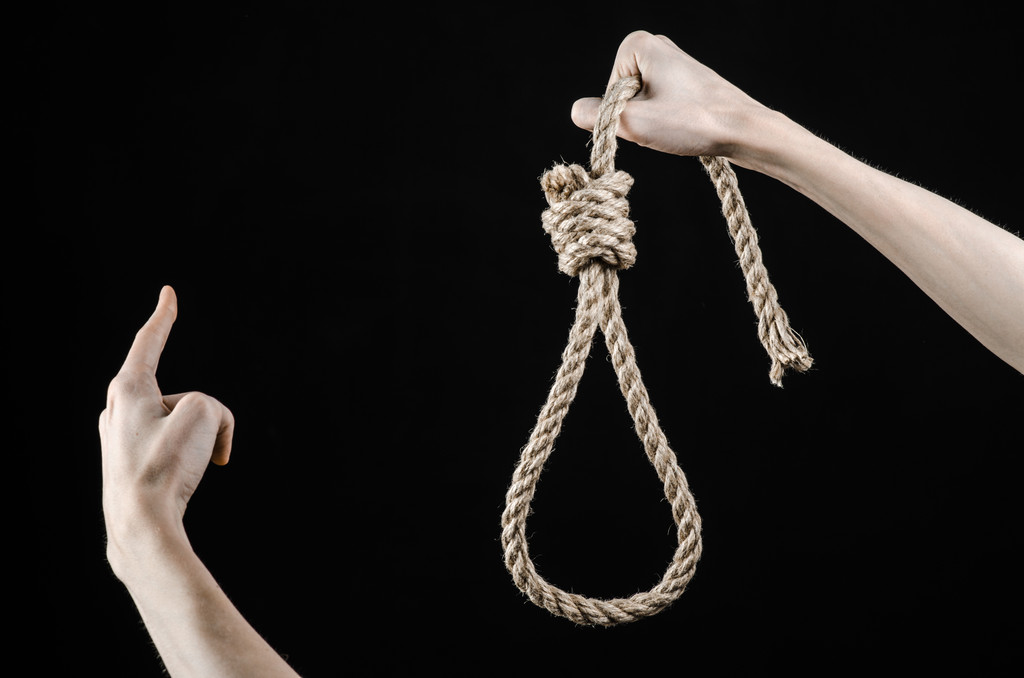Lynching and suicide theme: man's hand holding a loop of rope for hanging on black isolated background - Photo, Image