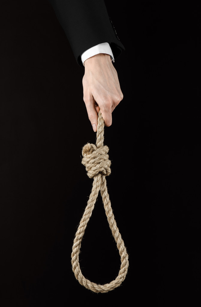自殺とビジネス トピック: 黒に掛かっているロープのループを保持している黒のジャケットで実業家の手孤立の背景 - 写真・画像