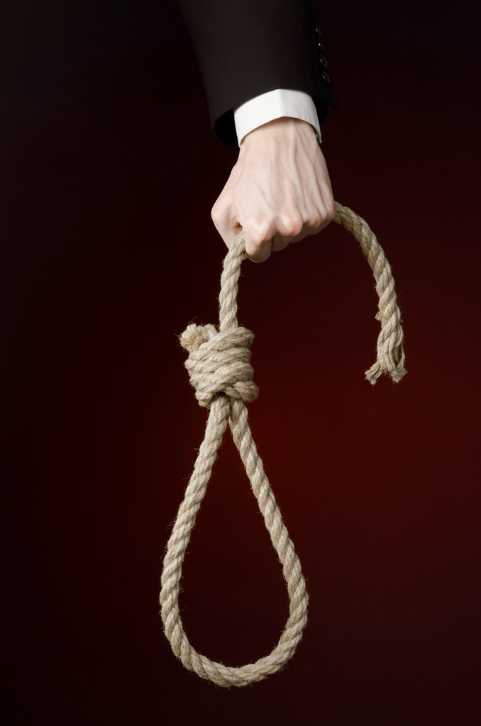 自殺とビジネスのトピック: 濃い赤に掛かっているロープのループを保持している黒のジャケットで実業家の手孤立の背景 - 写真・画像