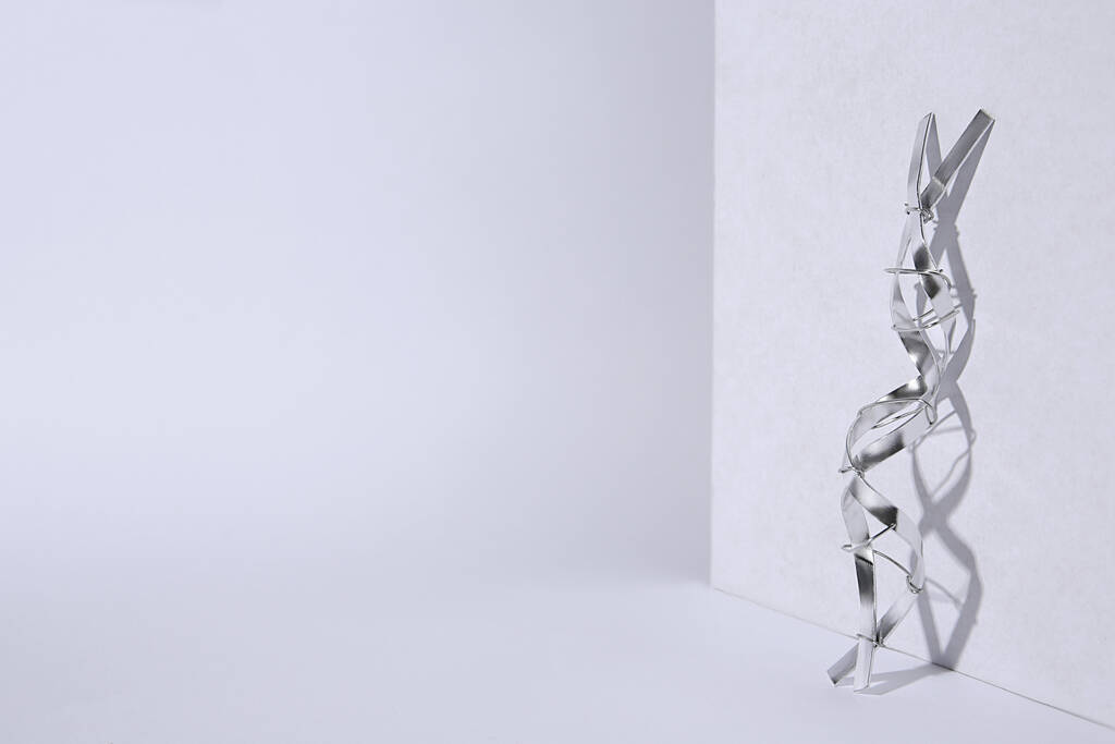 Modelo de cadeia molecular de DNA feito de metal sobre fundo branco, espaço para texto - Foto, Imagem